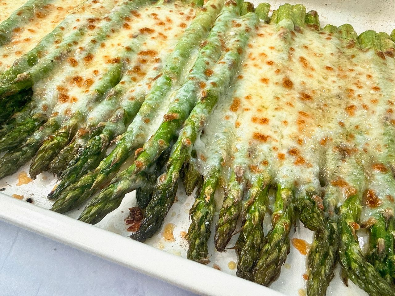 Cheesy Roasted Asparagus on a baking sheet with a white spatula