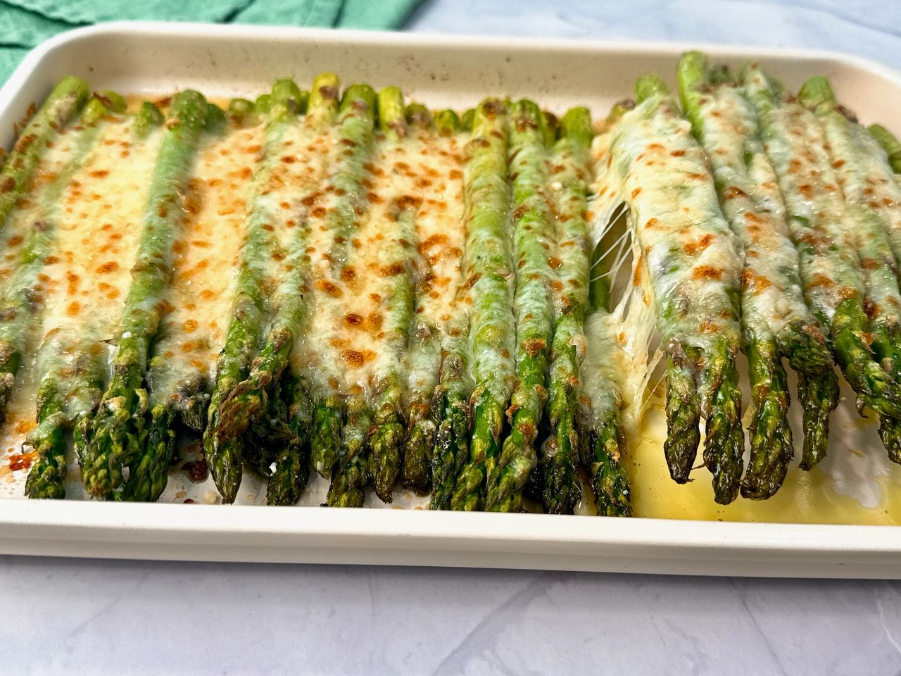 Cheesy Roasted Asparagus on a baking sheet with a white spatula