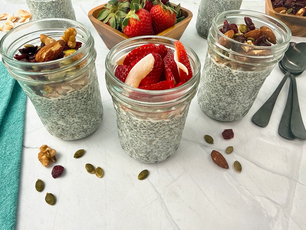 Chia Seed Pudding Chia Seed Pudding in mason jars with black spoons, fresh fruit, and granola