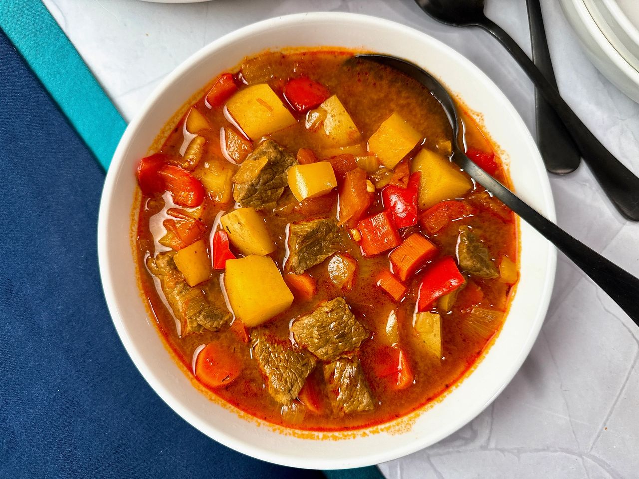 Hungarian Goulash Hungarian Goulash in a white bowl with a black spoon and blue napkins