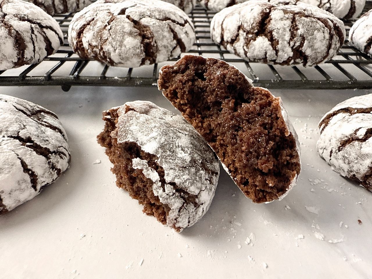 chocolate crinkle cookies on a wire rack and on a white surface