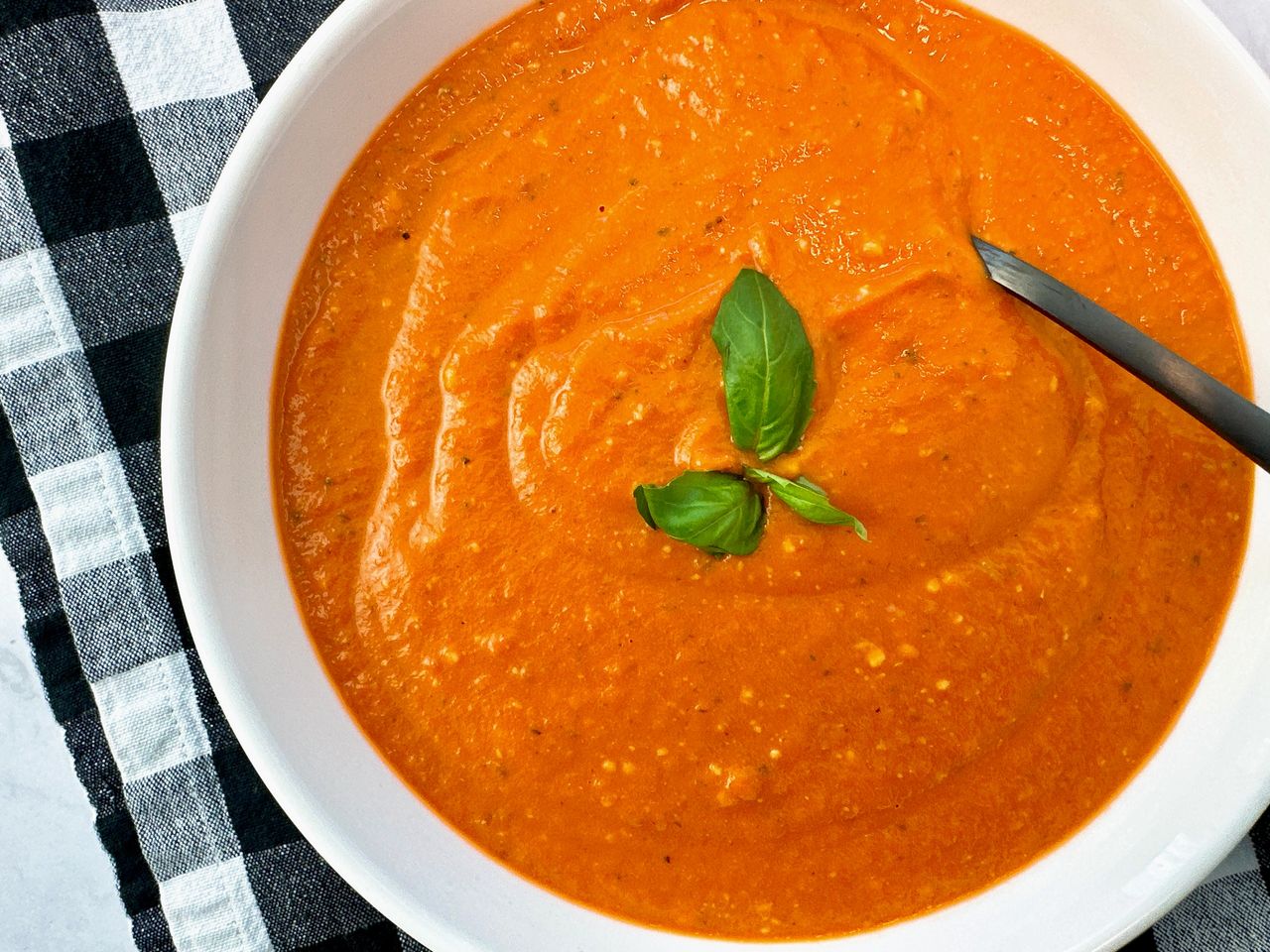 Creamy Tomato Soup in a white bowl with a black spoon