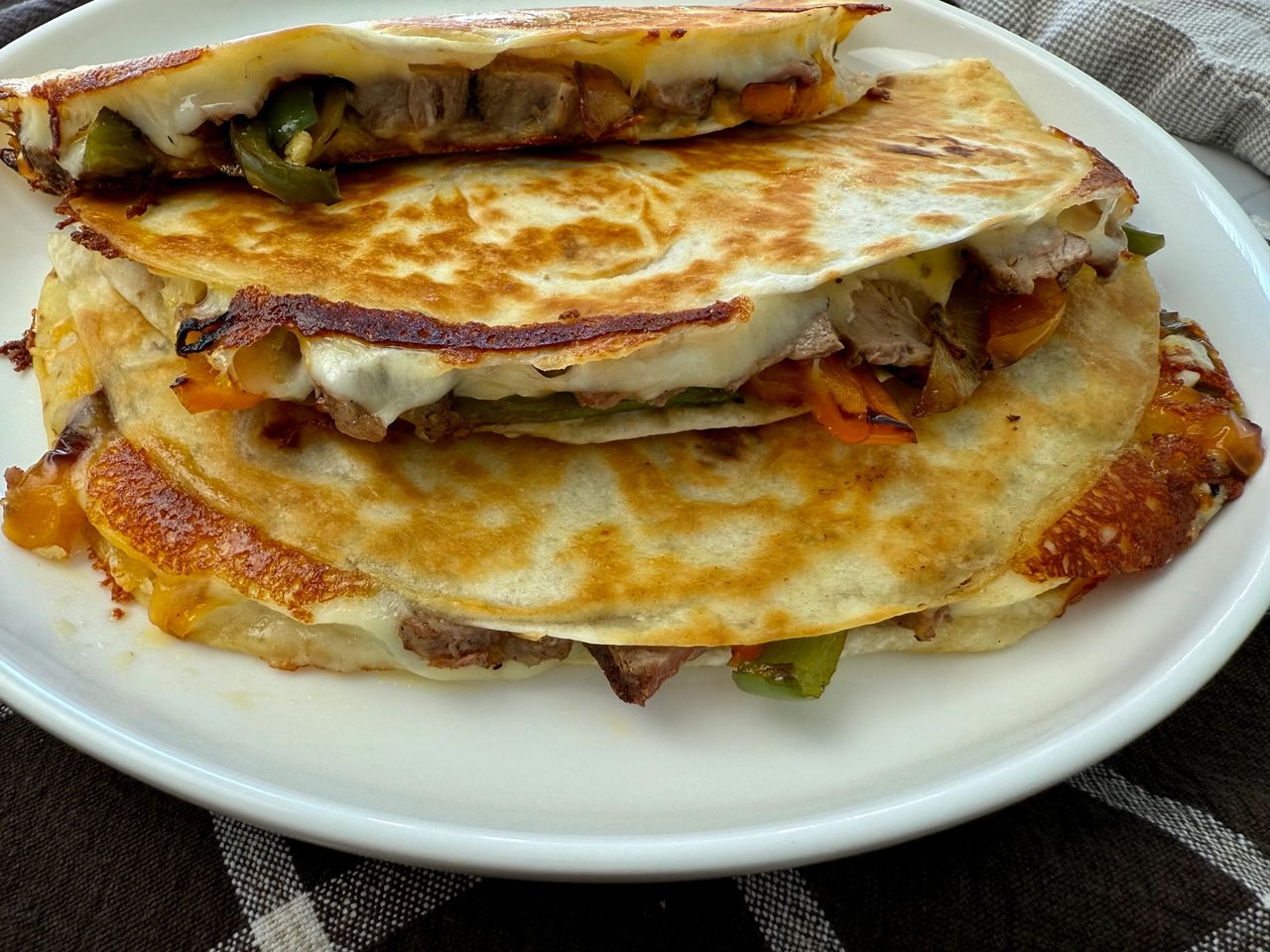 Philly Cheesesteak Quesadillas stacked on a white plate