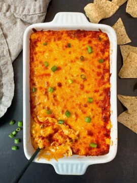 Buffalo Chicken Dip in a white dish with corn chips on a black surface