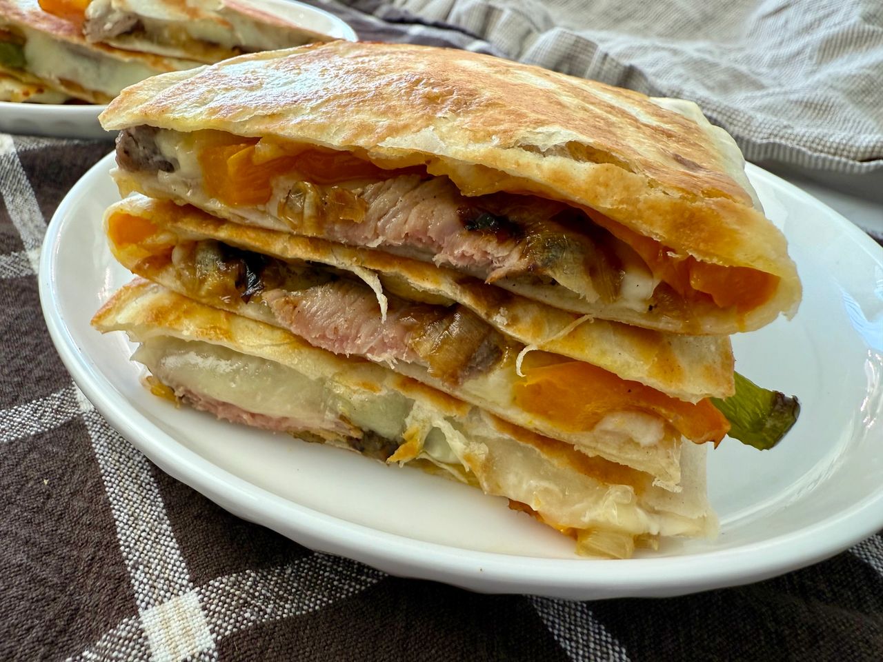 Philly Cheesesteak Quesadillas stacked on a white plate