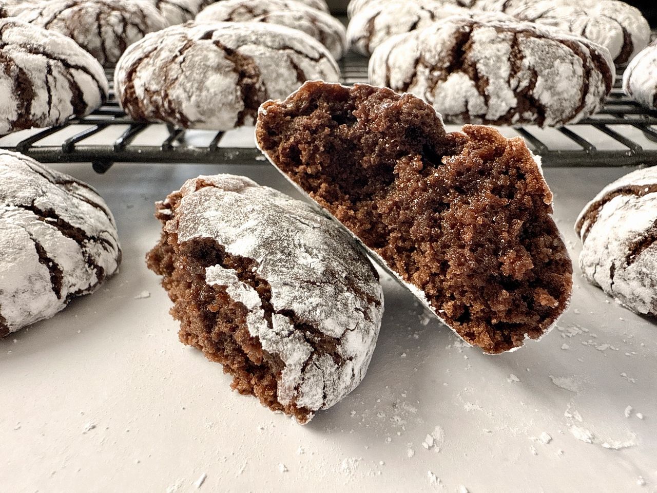 chocolate crinkle cookies on a wire rack and on a white surface