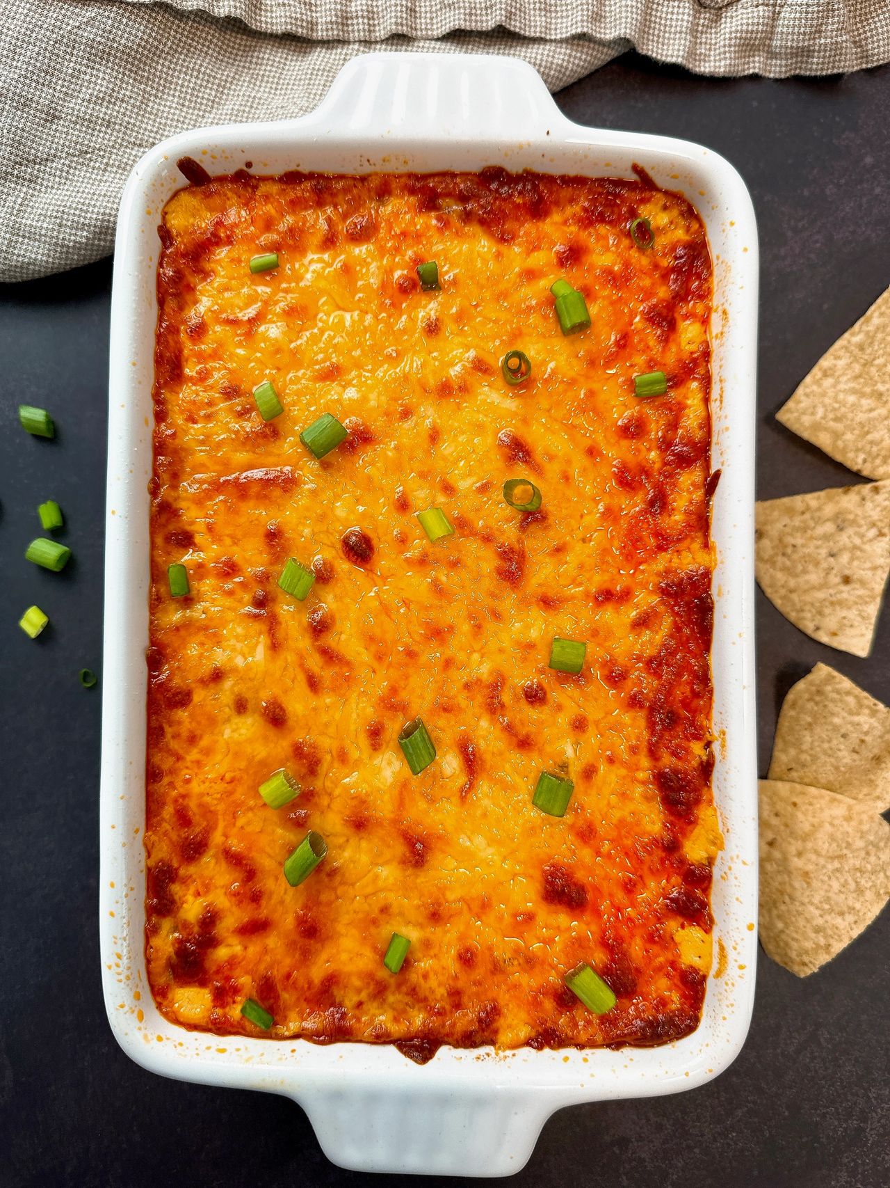 Buffalo Chicken Dip in a white dish with corn chips on a black surface