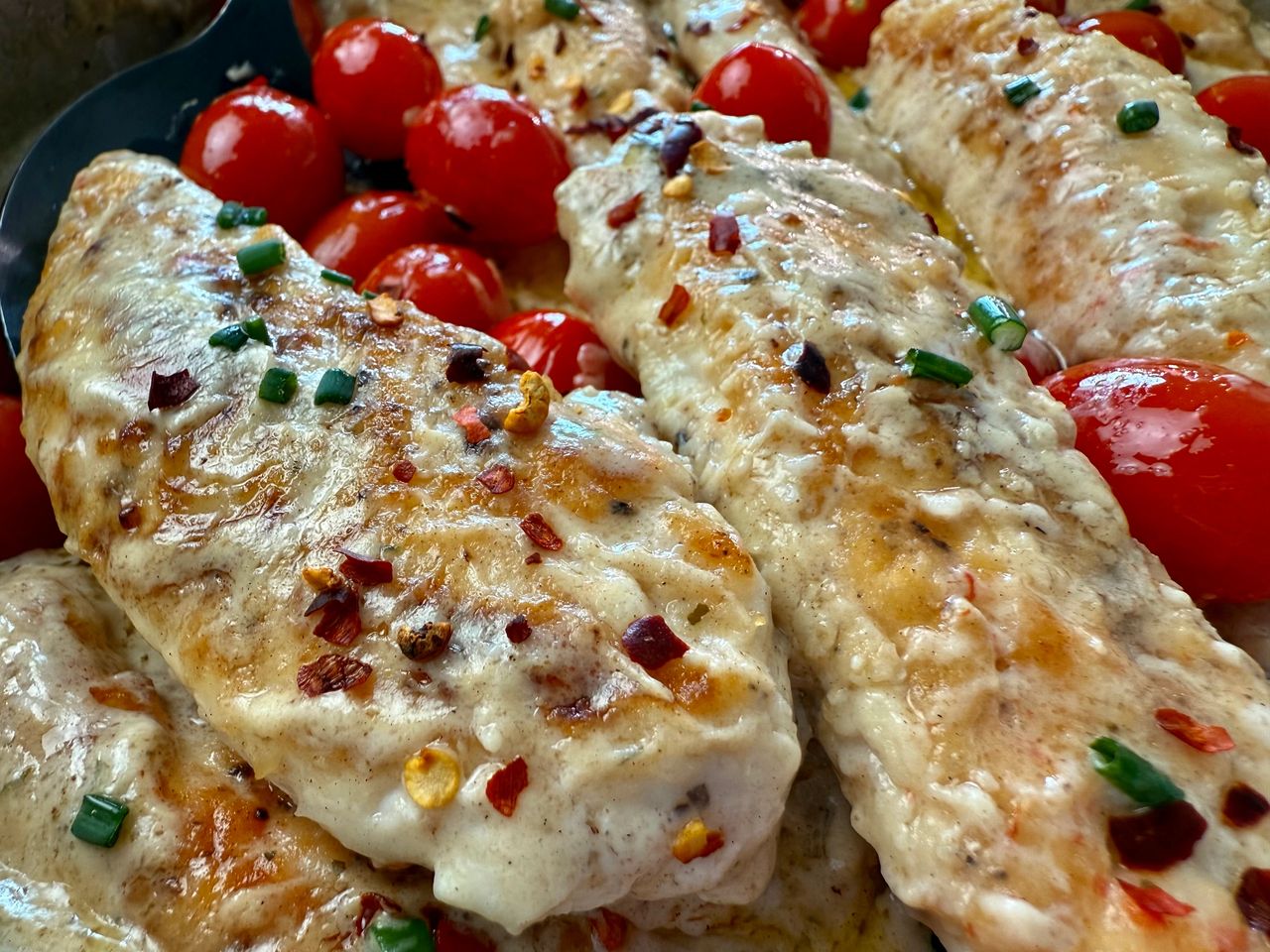 Boursin Chicken in a skillet with grape tomatoes
