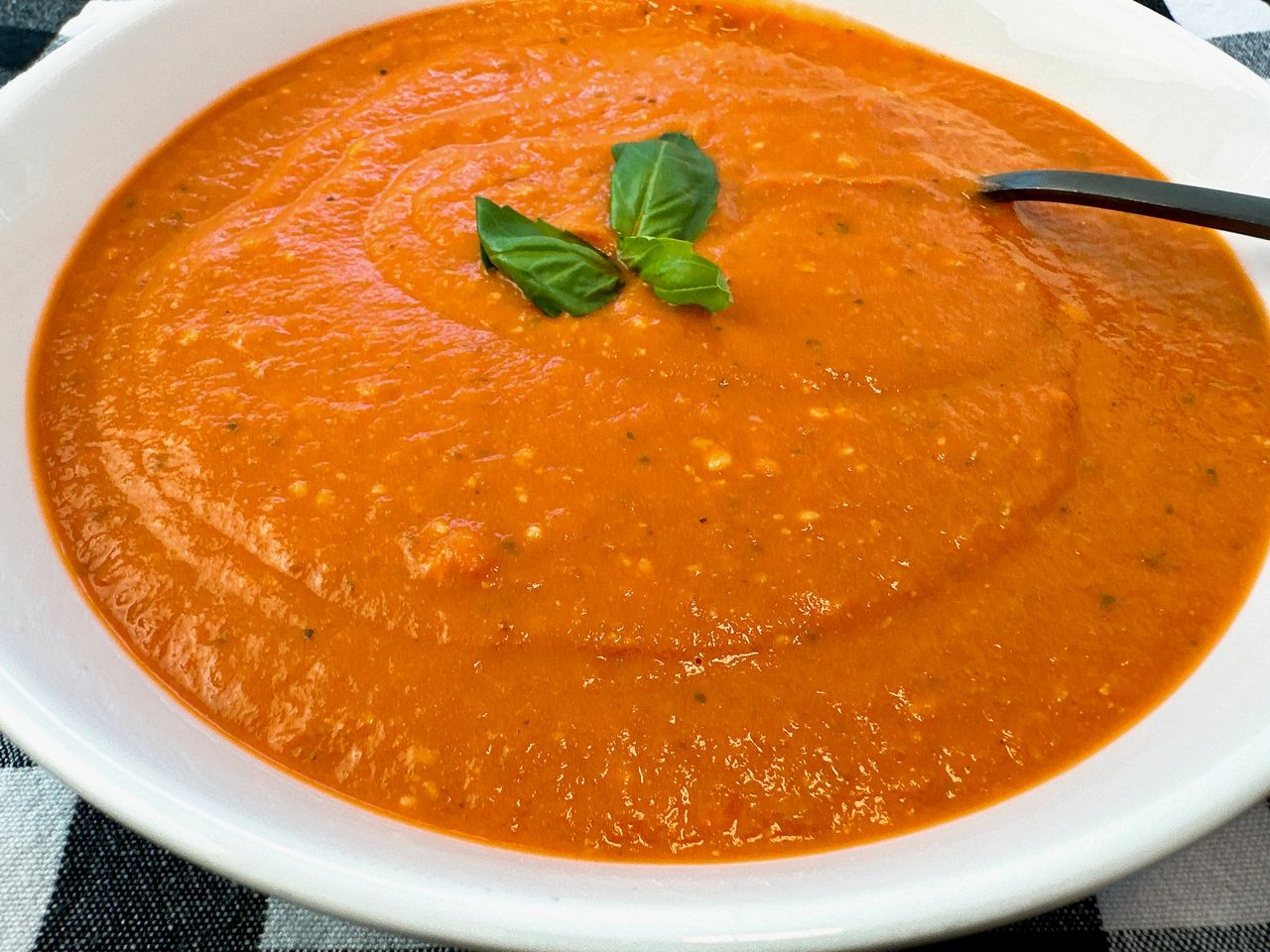 Creamy Tomato Soup in a white bowl with a black spoon