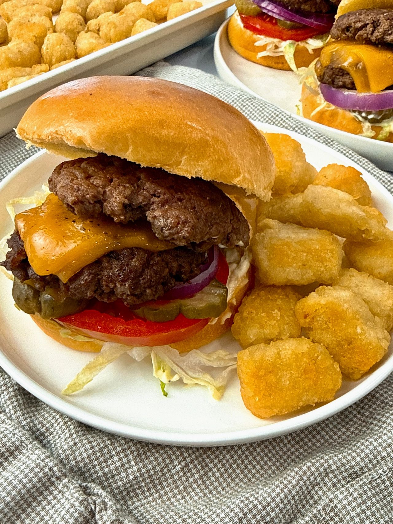 Smash Burgers on a white plate with tater tots