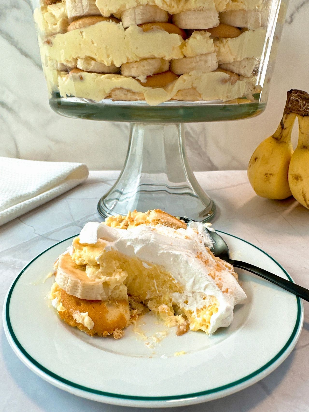 Banana Pudding in a tall clear dessert bowl and on a white dessert plate