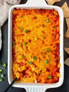 Buffalo Chicken Dip in a white dish with corn chips on a black surface