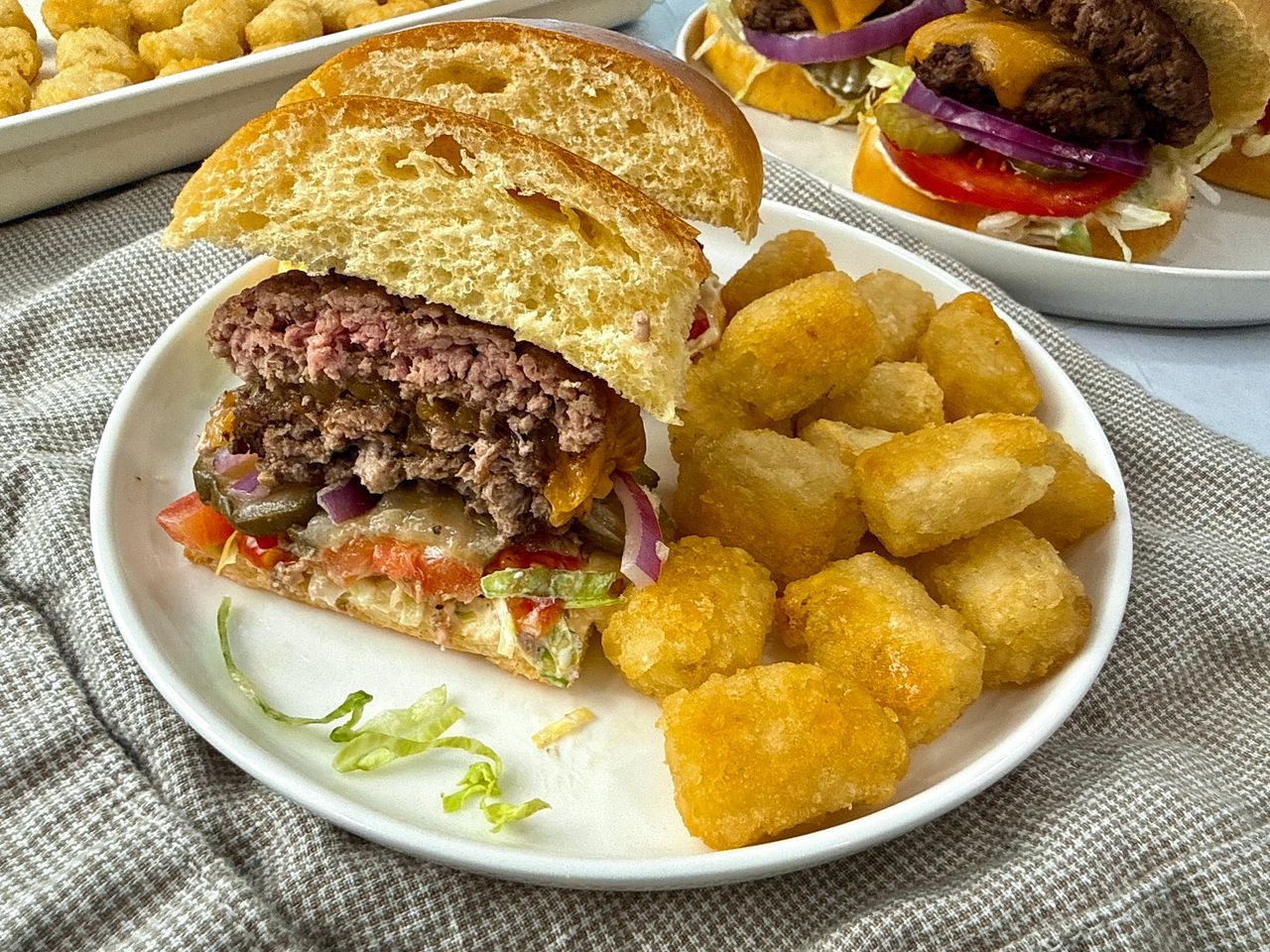 Smash Burgers on a white plate with tater tots