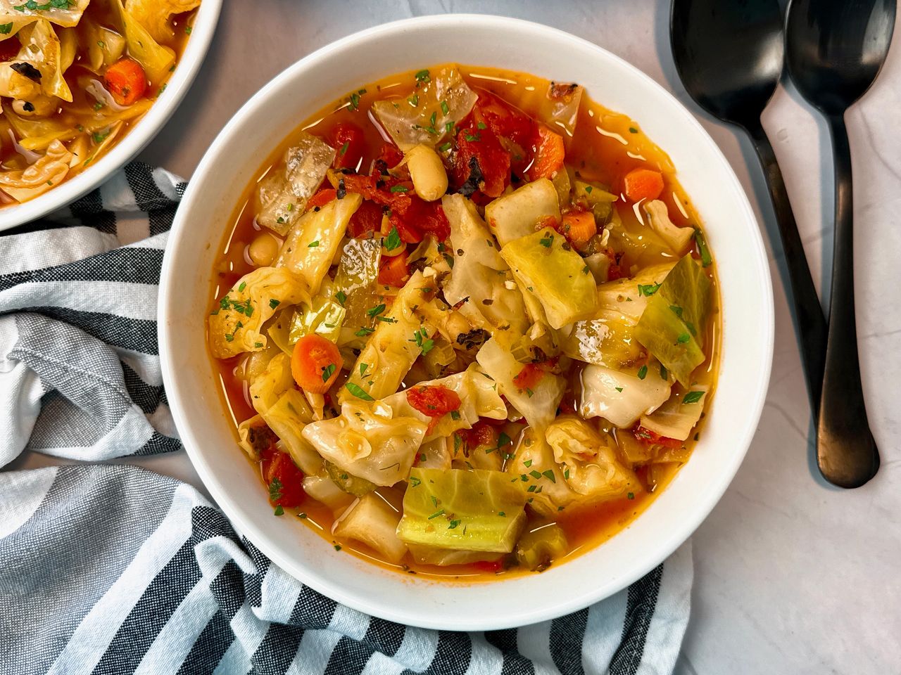 Cabbage Soup in a white bowl with a black spoon 