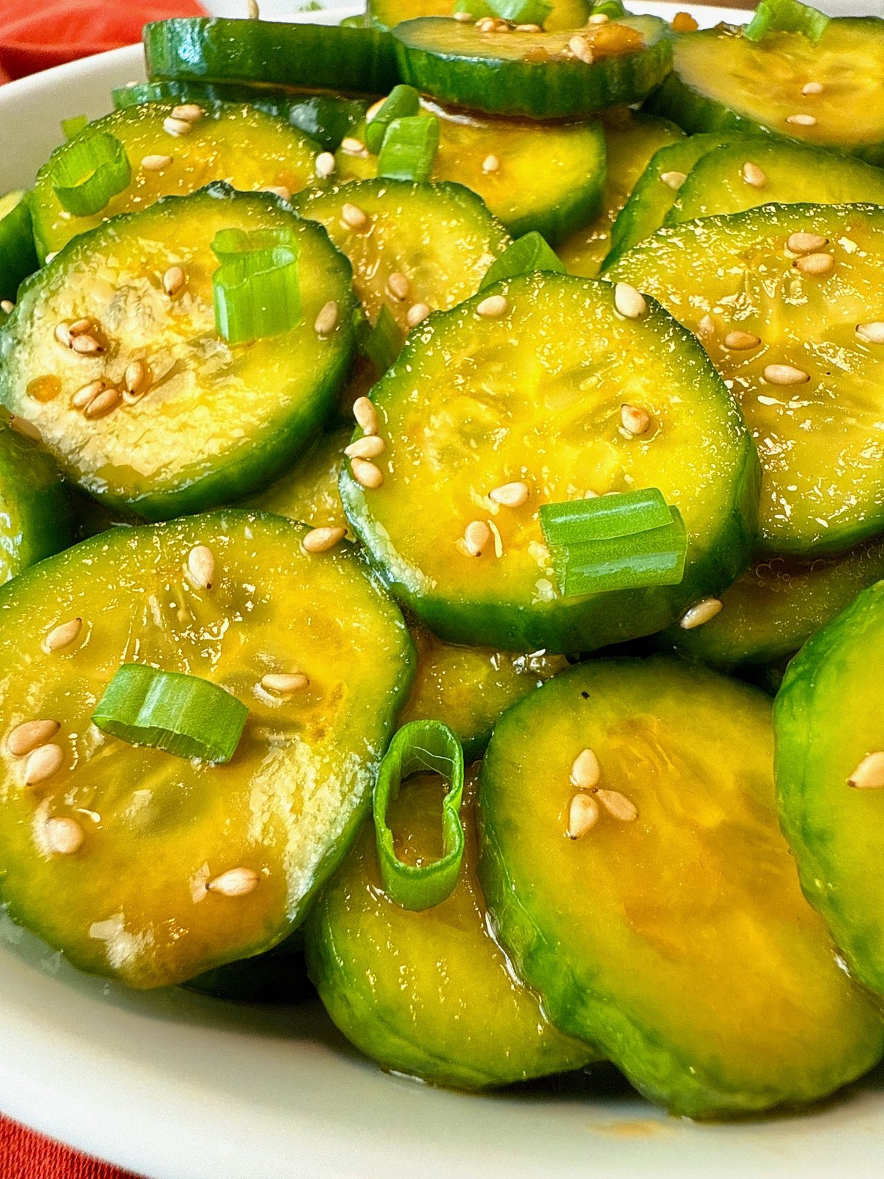 Asian Cucumber Salad in a white bowl with black chop sticks and red napkin