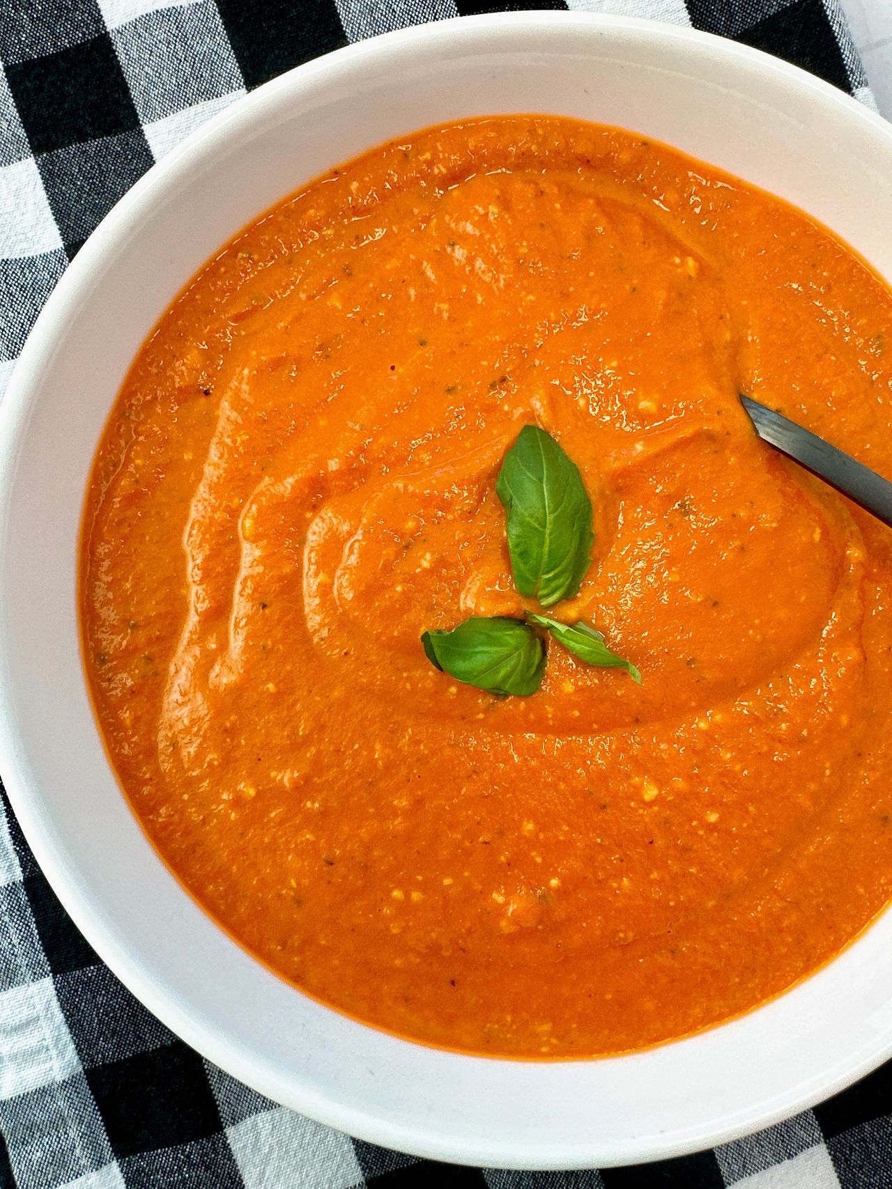 Creamy Tomato Soup in a white bowl with a black spoon