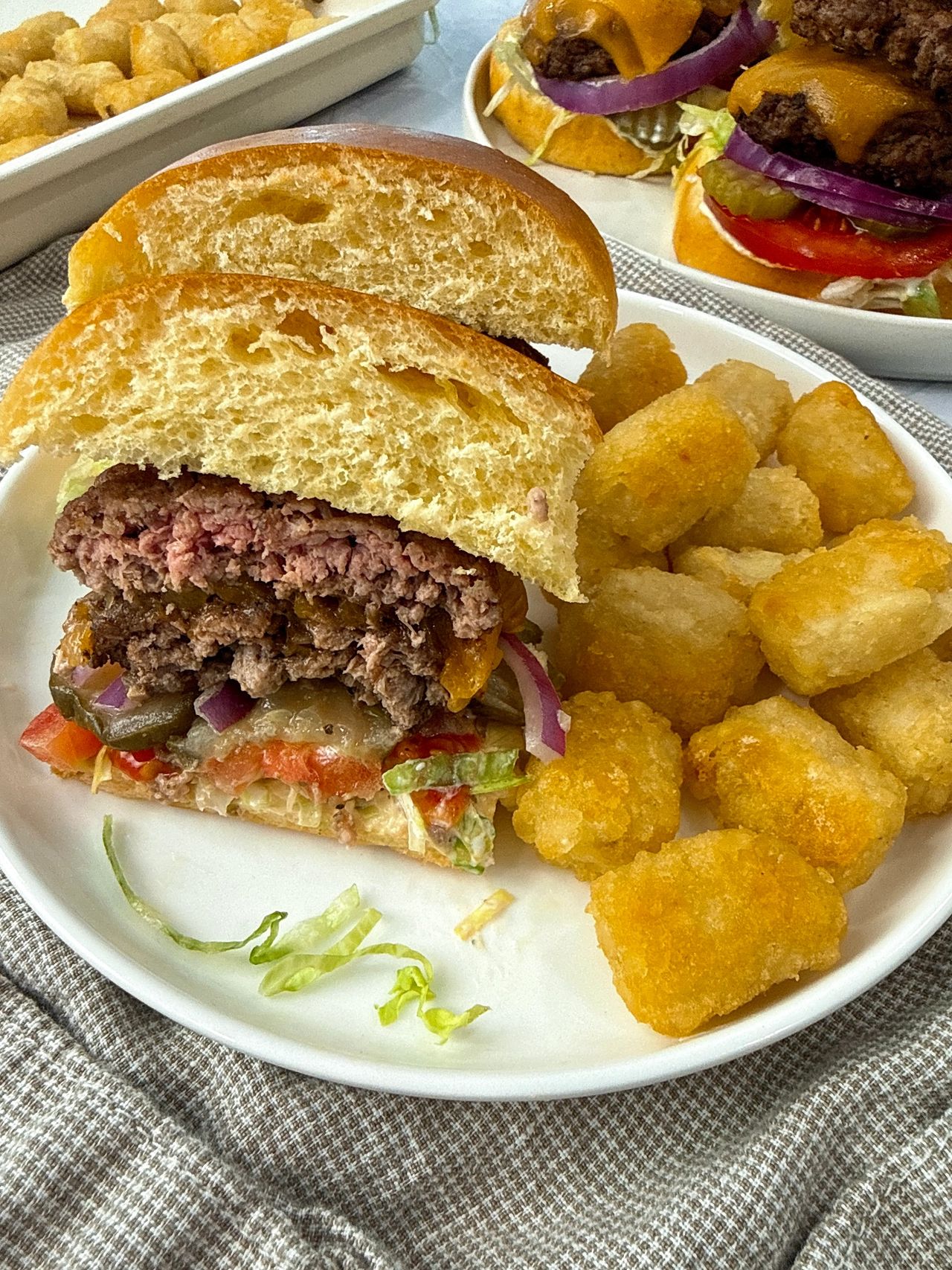 Smash Burgers on a white plate with tater tots