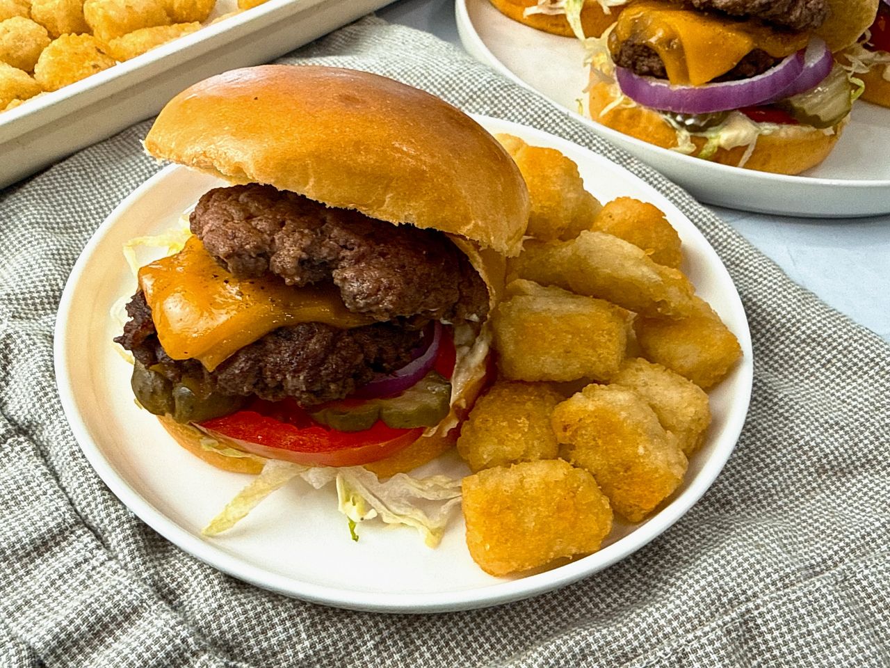 Smash Burgers on a white plate with tater tots