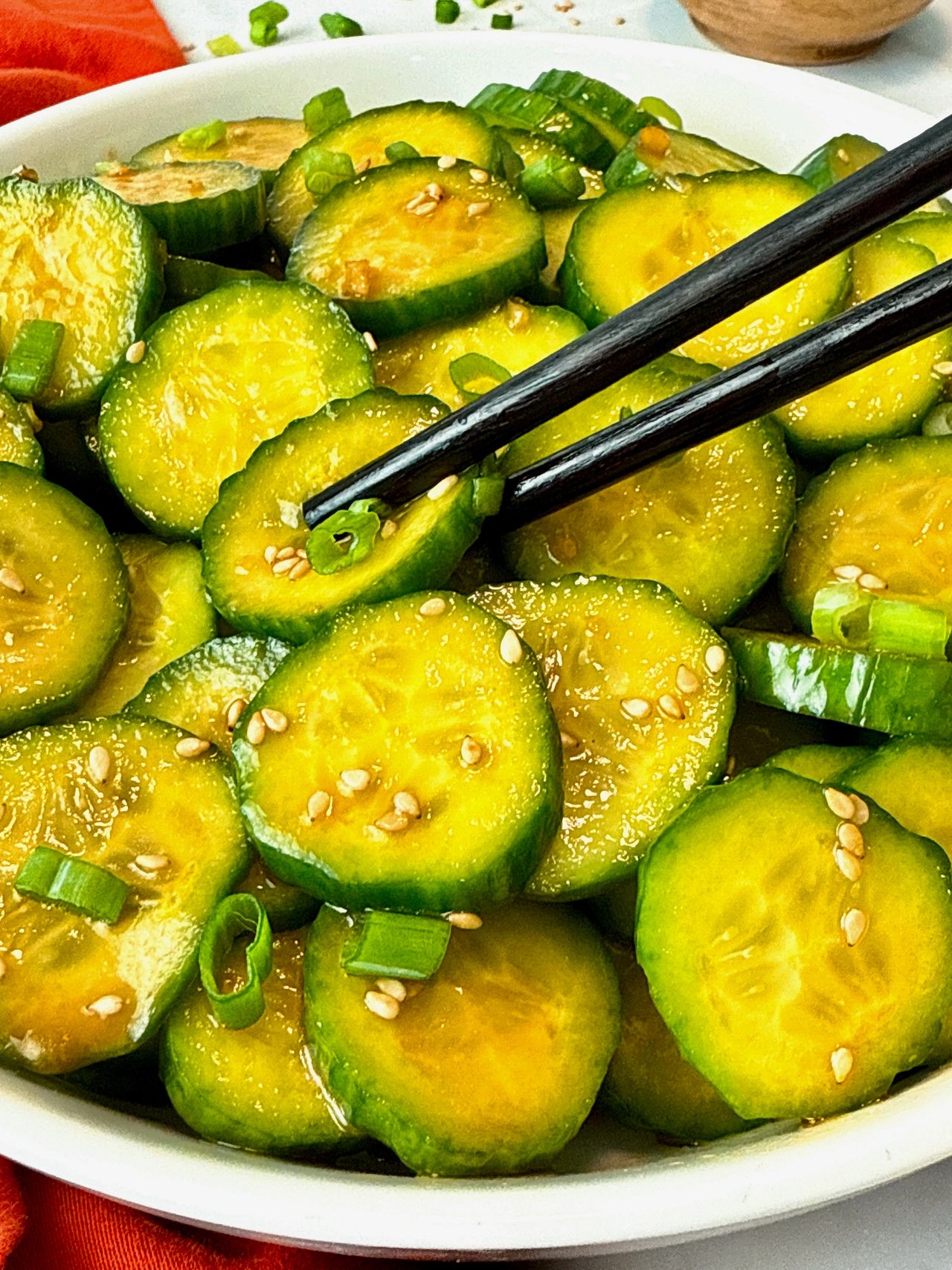 Asian Cucumber Salad in a white bowl with black chop sticks and red napkin