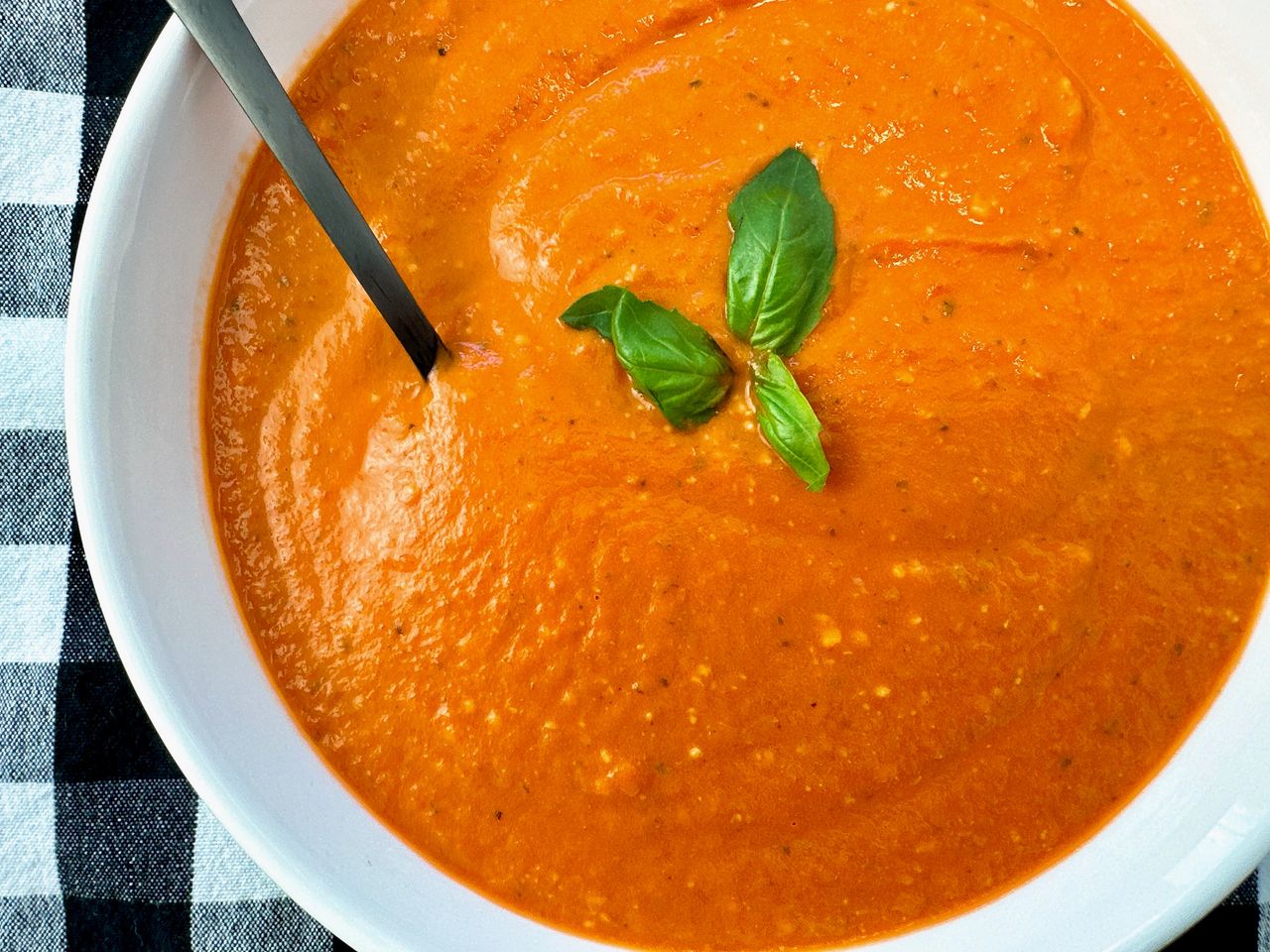 Creamy Tomato Soup in a white bowl with a black spoon