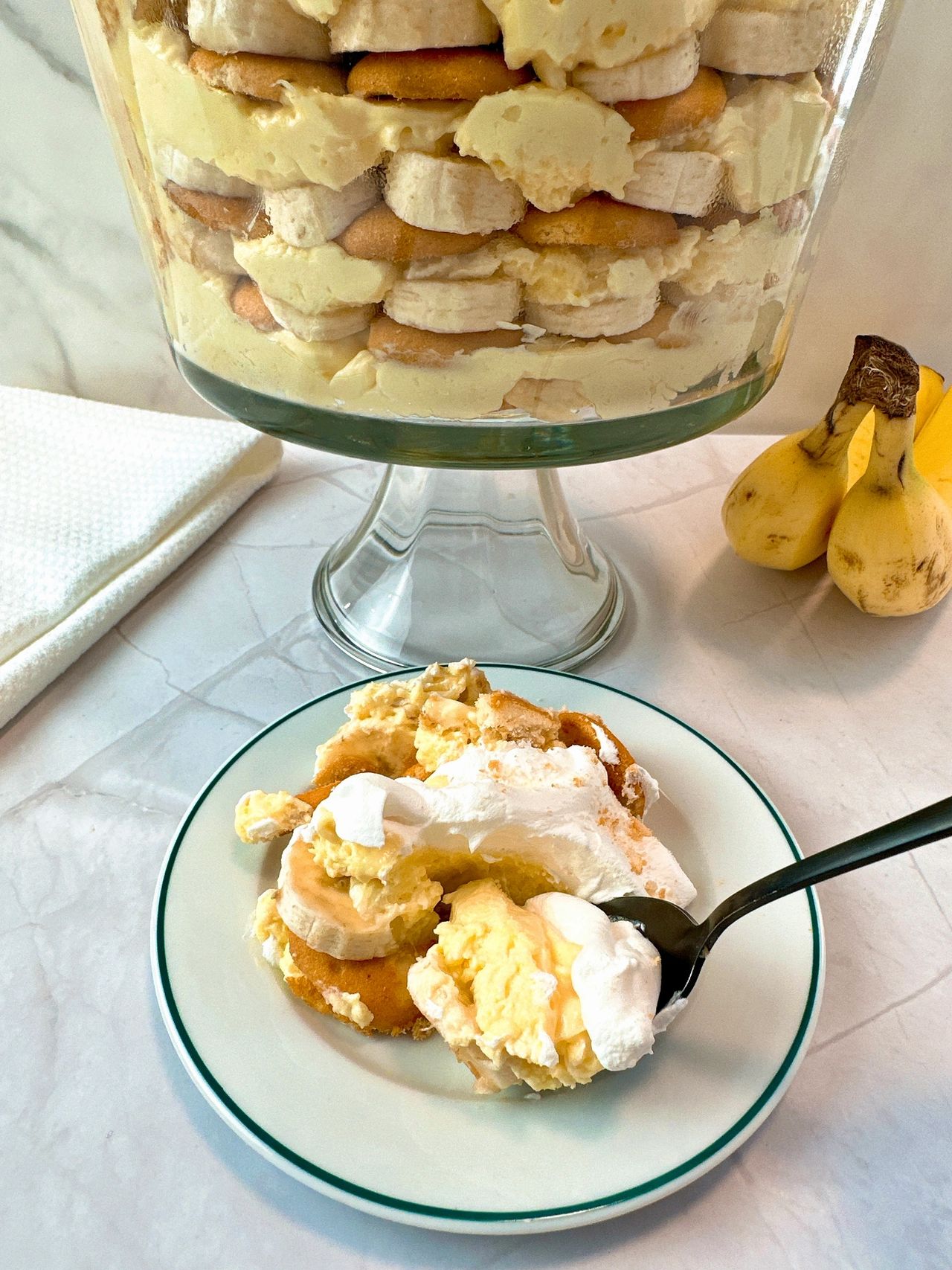 Banana Pudding in a tall clear dessert bowl and on a white dessert plate