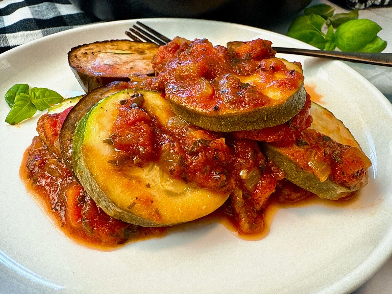 Ratatouille on a white plate with a black fork