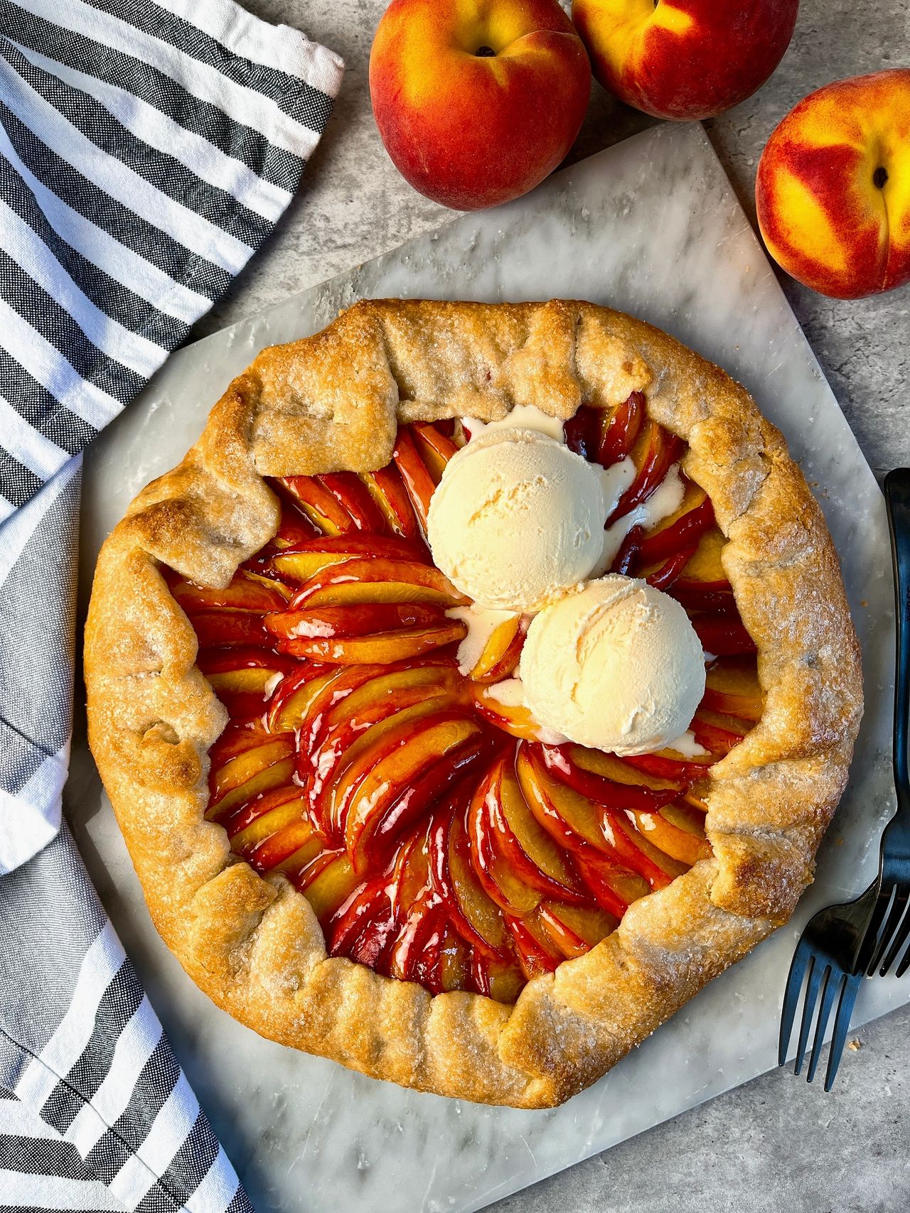 Easy Peach Galette on a marble surface with scoops of vanilla ice cream