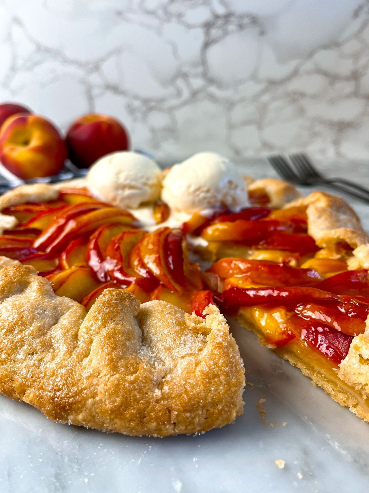 Easy Peach Galette on a white surface with vanilla ice cream