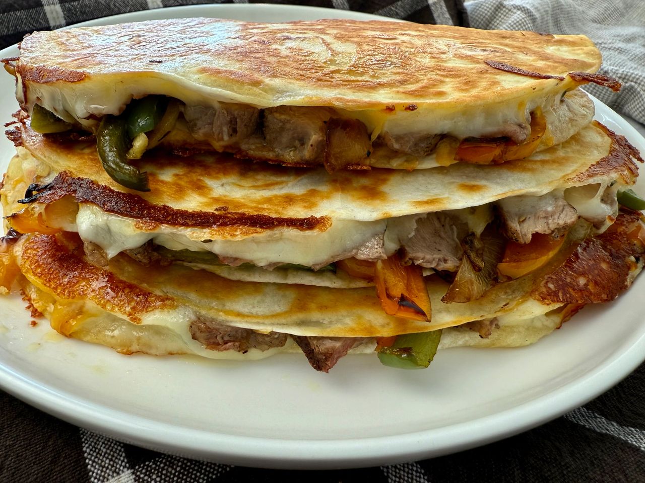Philly Cheesesteak Quesadillas stacked on a white plate