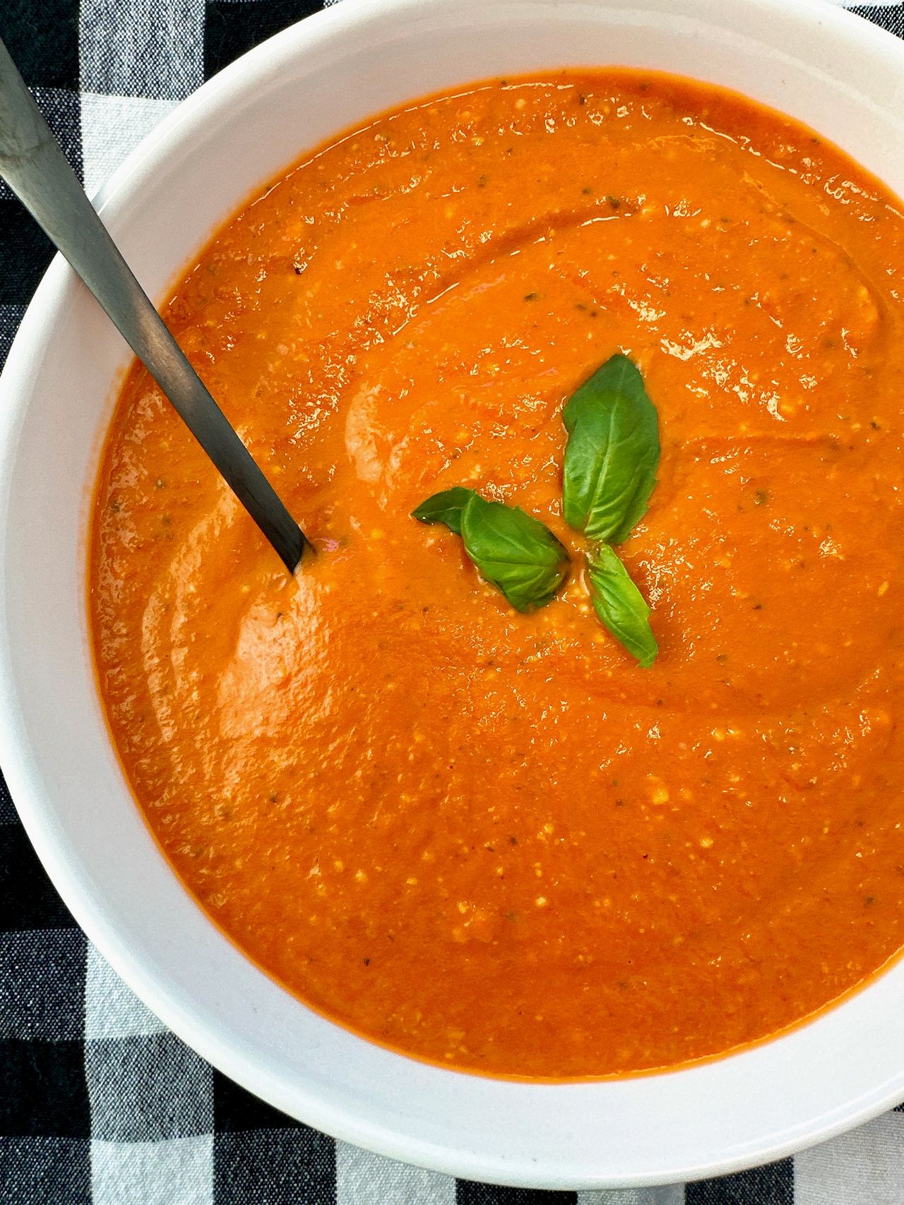 Creamy Tomato Soup in a white bowl with a black spoon