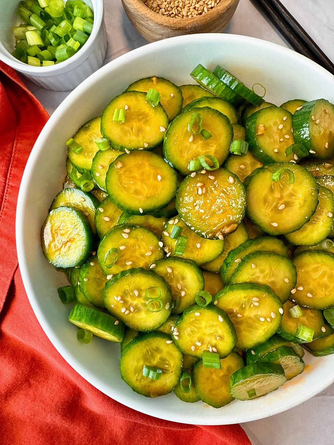 Asian Cucumber Salad in a white bowl with black chop sticks and red napkin