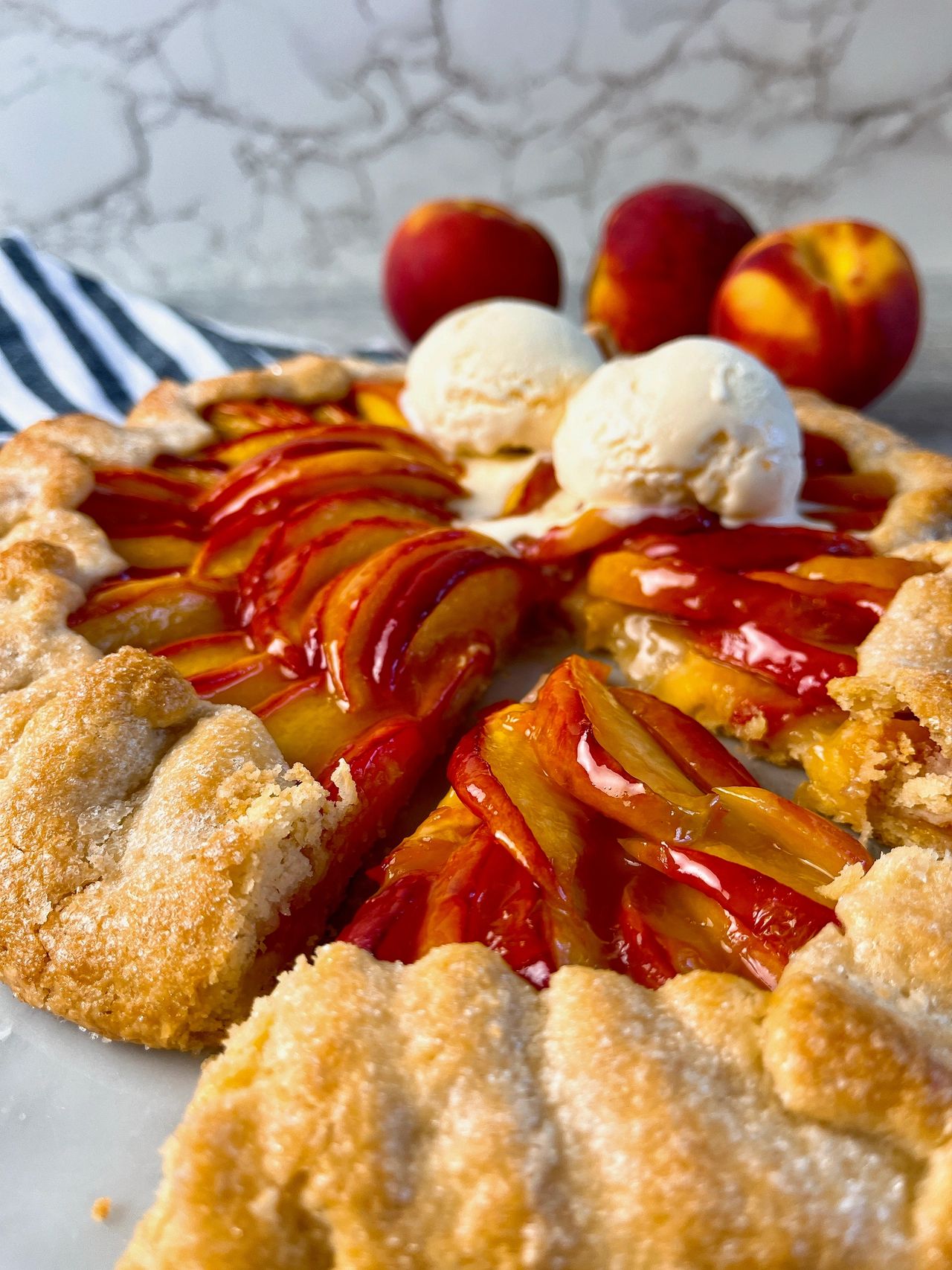 Easy Peach Galette on a white surface with vanilla ice cream