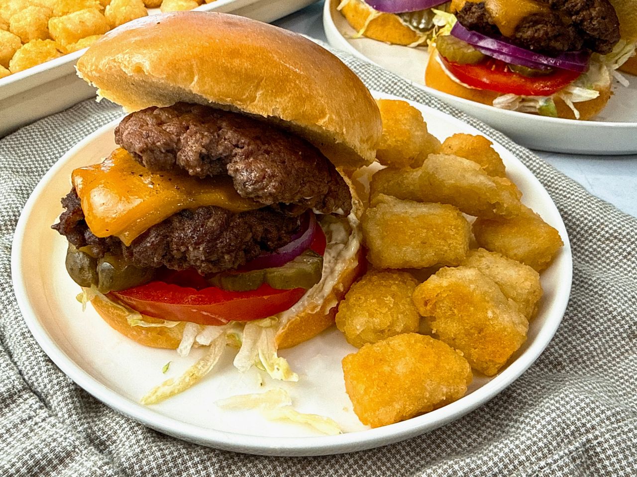 Smash Burgers on a white plate with tater tots