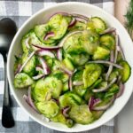 Cucumber Salad in a white bowl on a checkered towel