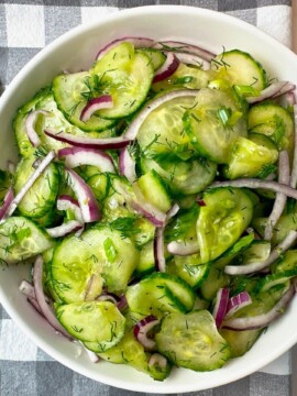 Cucumber Salad in a white bowl on a checkered towel