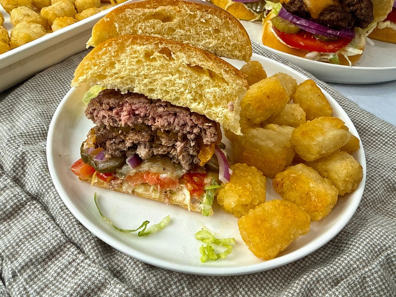 Smash Burgers on a white plate with tater tots