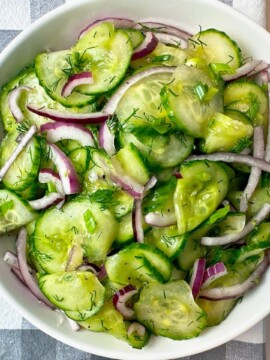 Cucumber Salad in a white bowl on a checkered towel