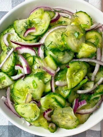 Cucumber Salad in a white bowl on a checkered towel