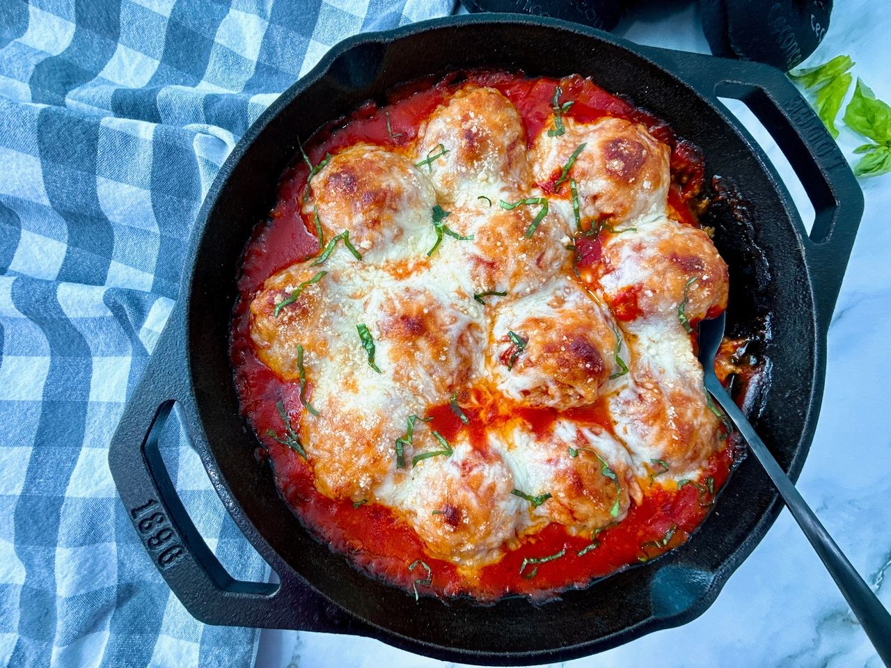 Chicken Parmesan Meatballs Chicken Parmesan Meatballs in a cast iron skillet with a black spoon and fresh basil