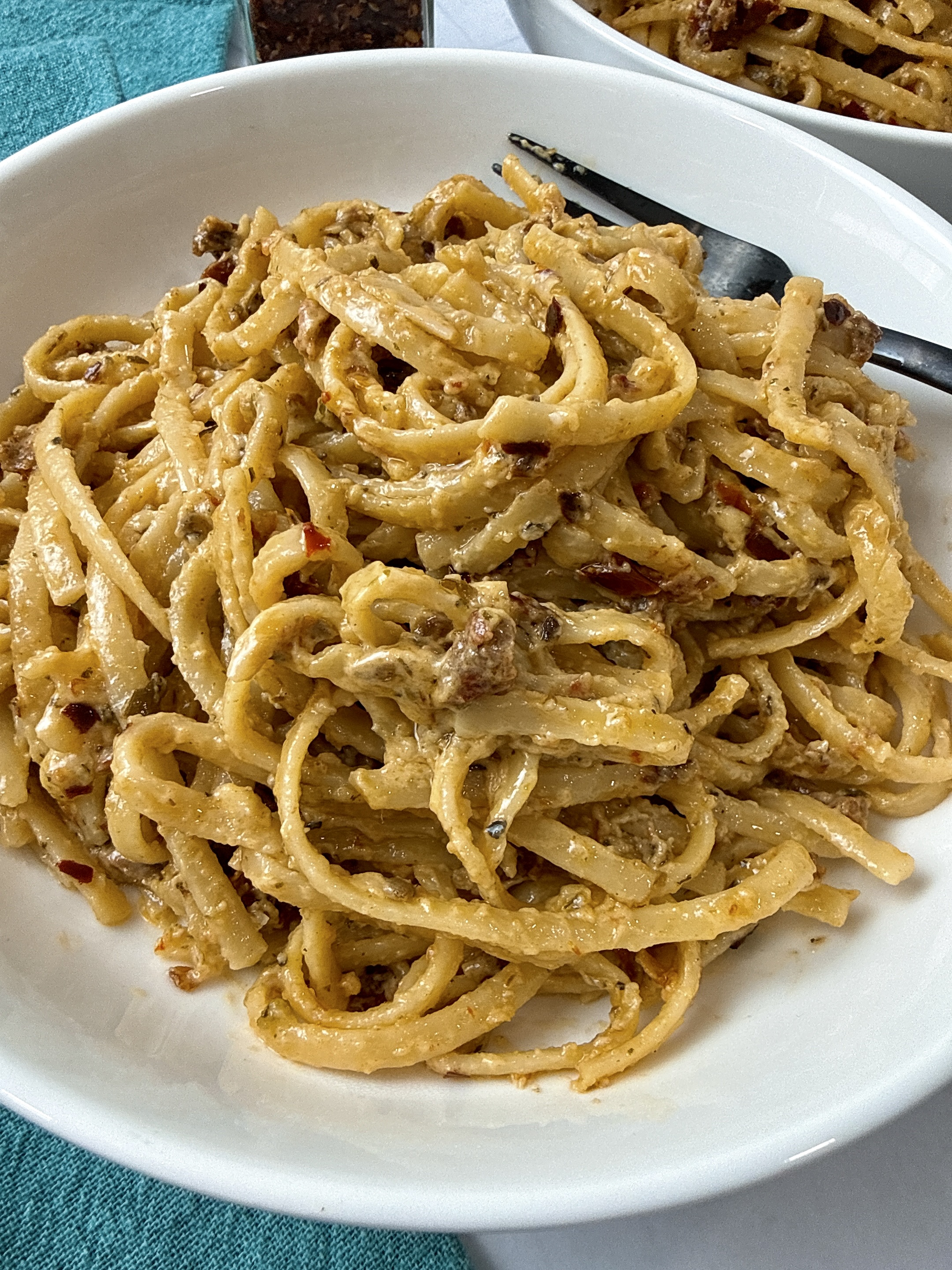 pasta with pesto and sun dried tomatoes in a white bowl