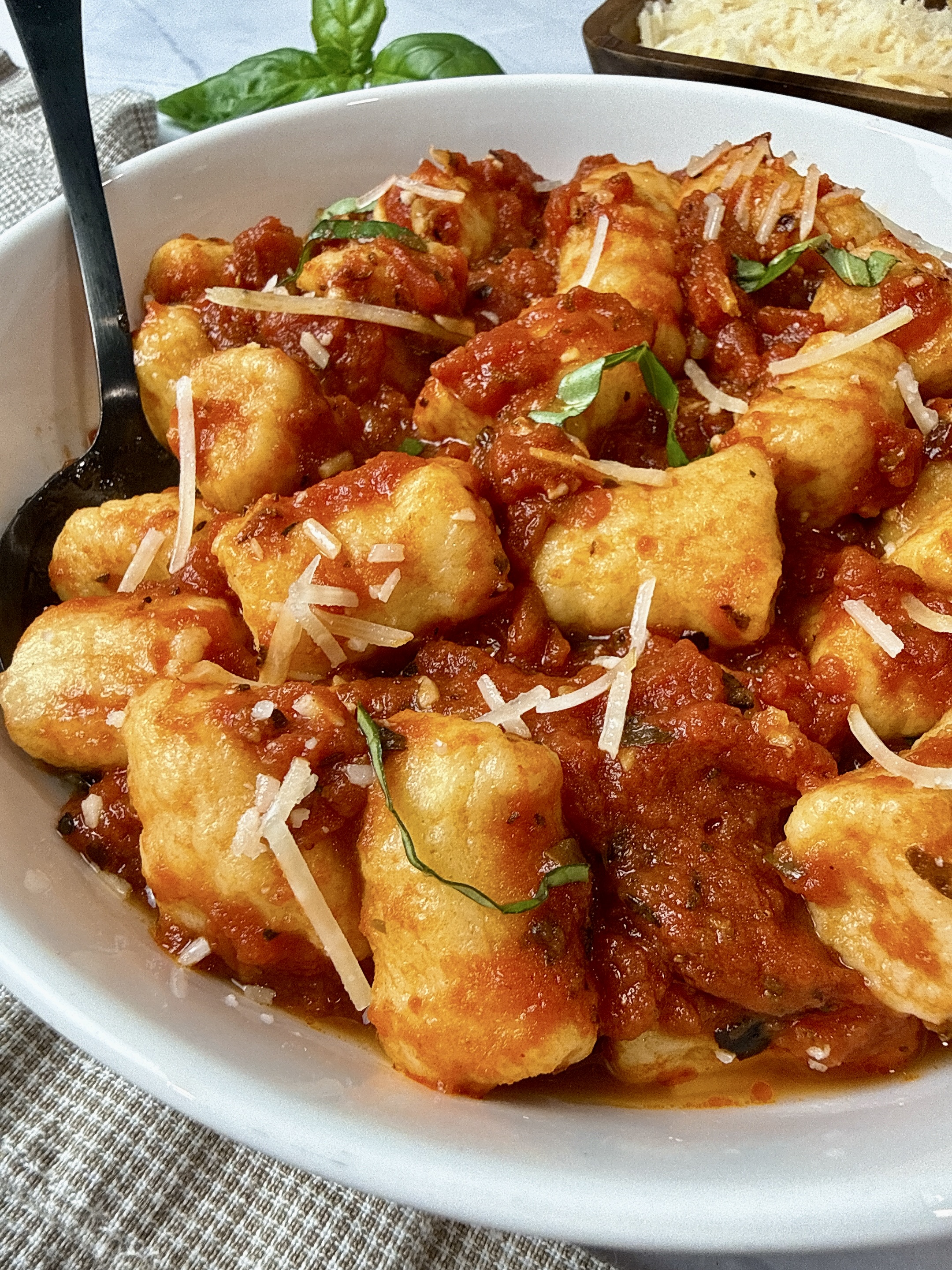Homemade Gnocchi with Tomato Sauce

Makes: 4 servings

Ingredients

For the gnocchi:

1 ¼ pounds Yukon gold potatoes (about 3 medium), or Russet potatoes (about 2 medium), scrubbed clean, skin on

1 cup all-purpose flour, plus more for coating your work surface

½ teaspoon salt

1 large egg, room temperature

For the sauce:

1 tablespoon olive oil

2 cloves garlic, minced or pressed

1 teaspoon Italian herb seasoning, or dried oregano

1 teaspoon dried basil

½ teaspoon crushed red pepper flakes, or more/less to taste

28-ounce can whole peeled San Marzano tomatoes

Salt and black pepper

Fresh basil for serving

Grated or shredded parmesan cheese for serving

Instructions

Place the potatoes in a large saucepan and pour over enough cold water to cover.

Set the pan over high heat and bring to a boil. Boil for 12 to 15 minutes, until the potatoes are fork tender.

Drain and, when cool enough to handle, remove the potato skin.

Press the potatoes through a potato ricer or fine sieve. Set aside.

On a large, clean surface, combine the flour and salt and mix with your fingers to combine.

Make a well in the center of the flour mixture and add the egg and riced potatoes to the well.

Using your hands, mix the flour, potatoes, and egg together until you have a soft dough. The dough should not be sticky; if it is, add a small amount of flour.

Working on a lightly floured surface, shape the dough into 5 to 6 ropes, each about ½-inch thick. Cut the ropes crosswise into ¾-inch-long pieces.

Gently roll the pieces over the back of a fork to create tine marks.

Transfer the gnocchi to a parchment paper-lined baking sheet, in a single layer without touching, and let stand for 30 minutes.

Meanwhile, to make the tomato sauce, heat the oil in a large saucepan over medium heat. 

Add the garlic, Italian seasoning, basil, and red pepper flakes and cook for 30 seconds.

Add the tomatoes with the liquid from the can and bring to a simmer.

Reduce the heat to medium-low and simmer for 15 minutes.

Using a potato masher or fork, smash the tomatoes to create a thick, chunky sauce.

Season the sauce with salt and pepper.

To cook the gnocchi, bring a large pot of salted water to a boil.

Add the gnocchi and cook until they float to the top, about 1 to 3 minutes.

As soon as the gnocchi float, use a slotted spoon or fine mesh strainer to transfer them to the sauce.

Cook for 1 minute to heat through.

Top the gnocchi with fresh basil and serve with parmesan cheese on the side.