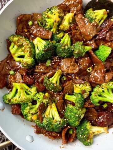 beef and broccoli in a white skillet