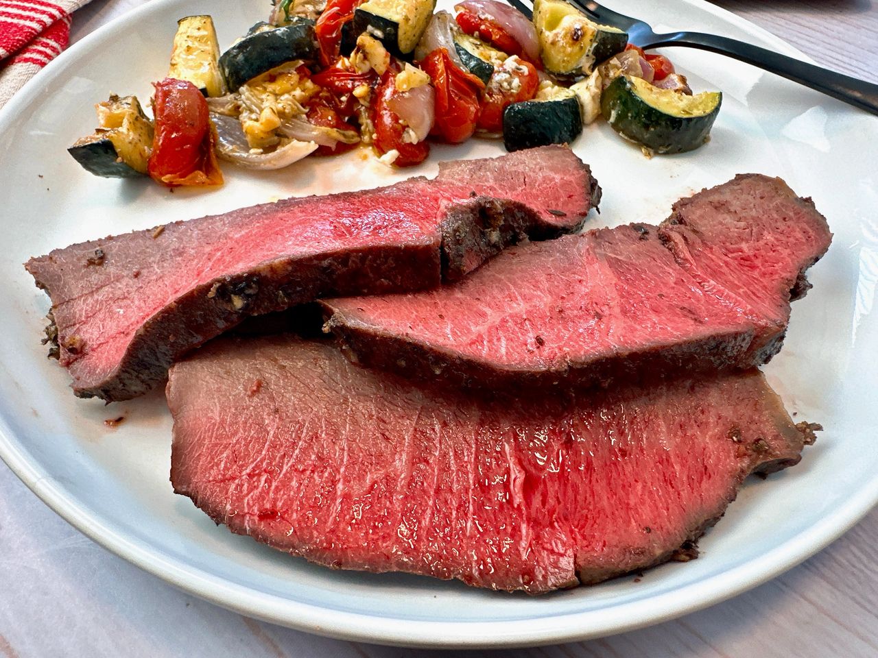 sirloin tip roast on a white plate with vegetables