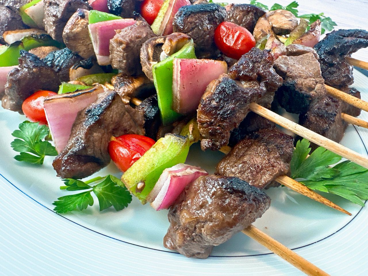 beef and vegetable kebabs on a white serving plate
