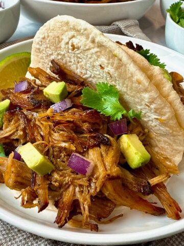 pork carnitas with avocado on a white plate