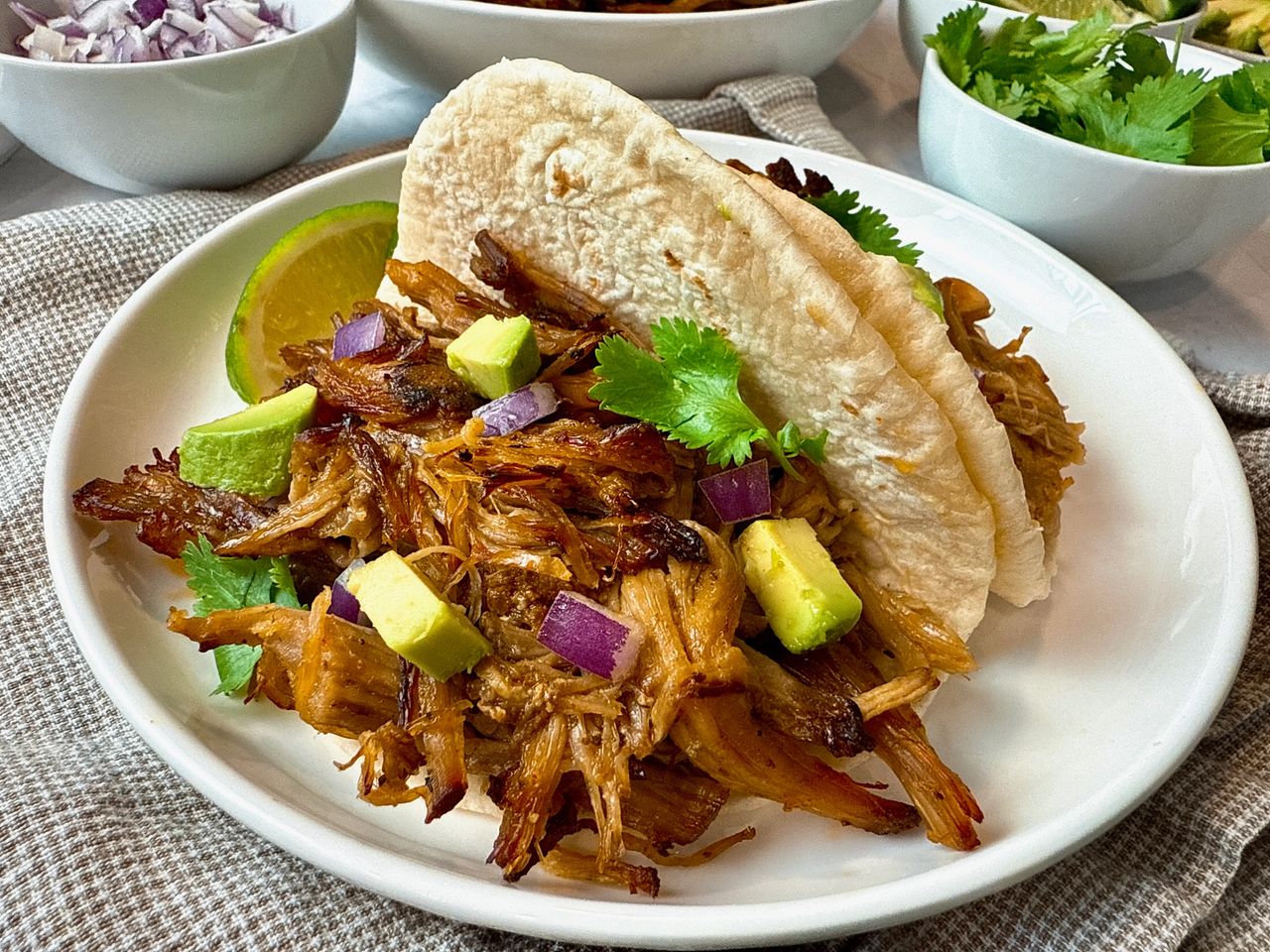 pork carnitas with avocado on a white plate