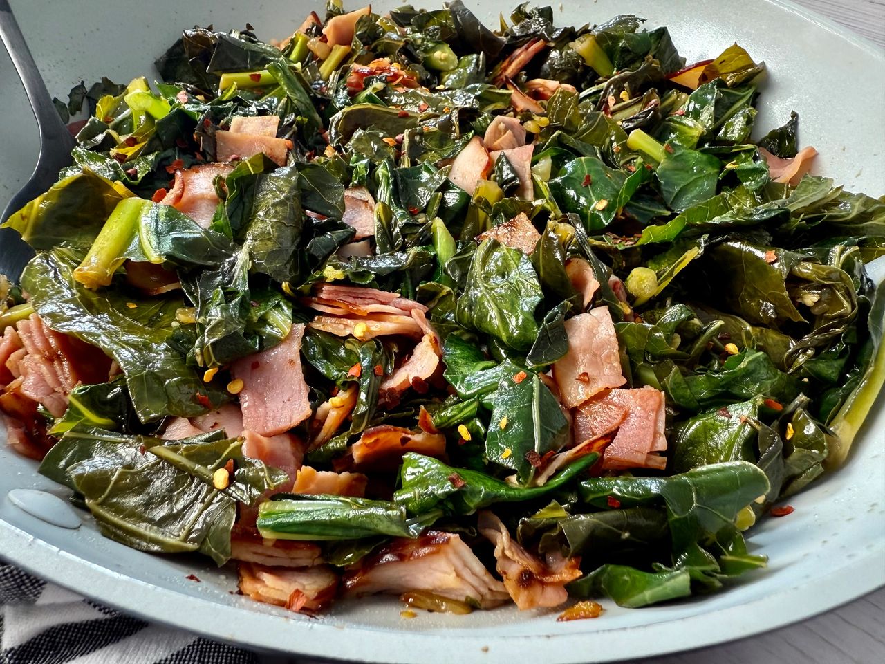 collard greens and ham in a white skillet