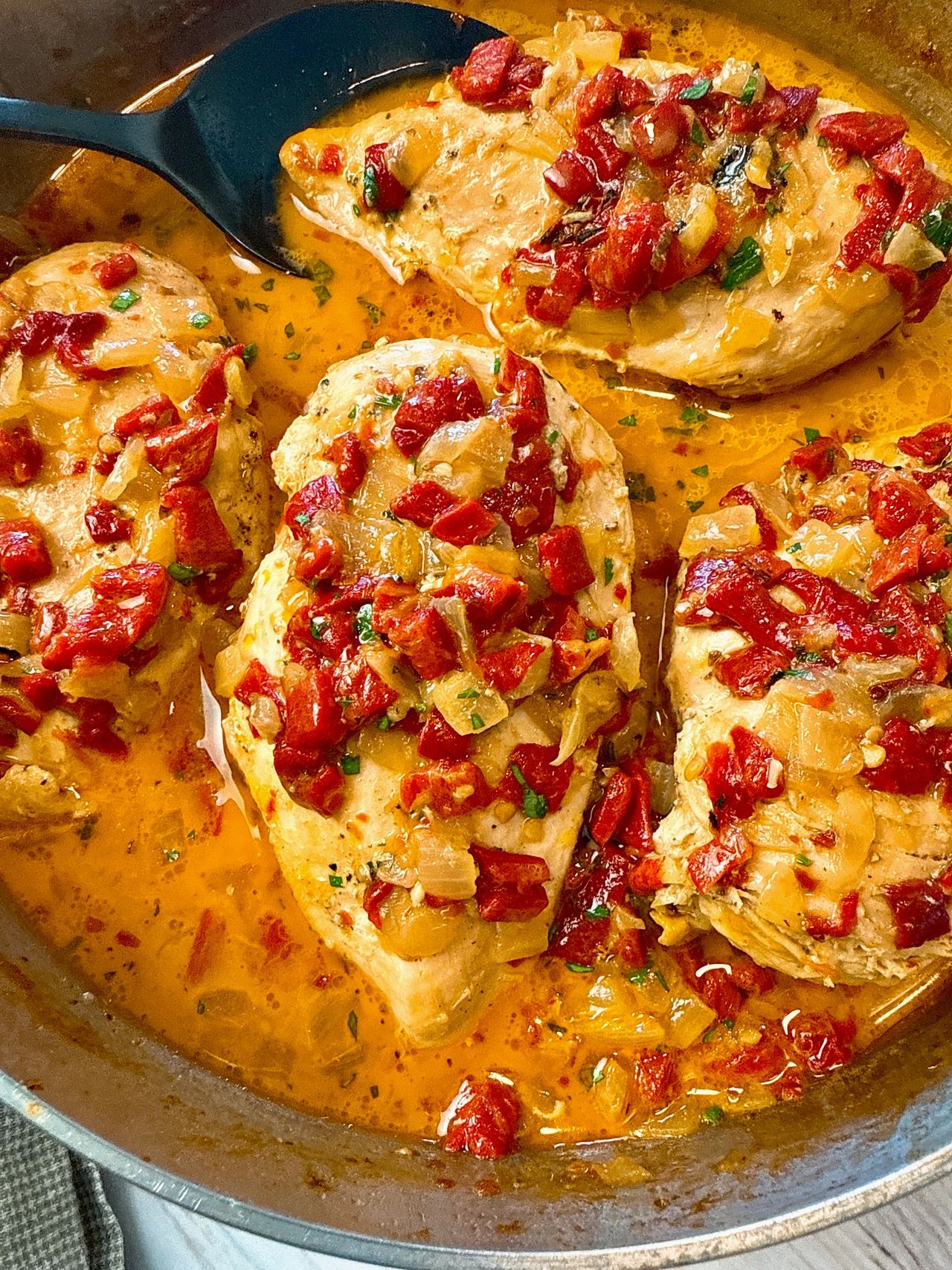 chicken breast with roasted red peppers over rice on a white plate