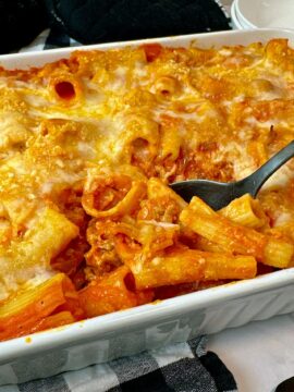 pasta and sausage in a casserole dish and white bowl