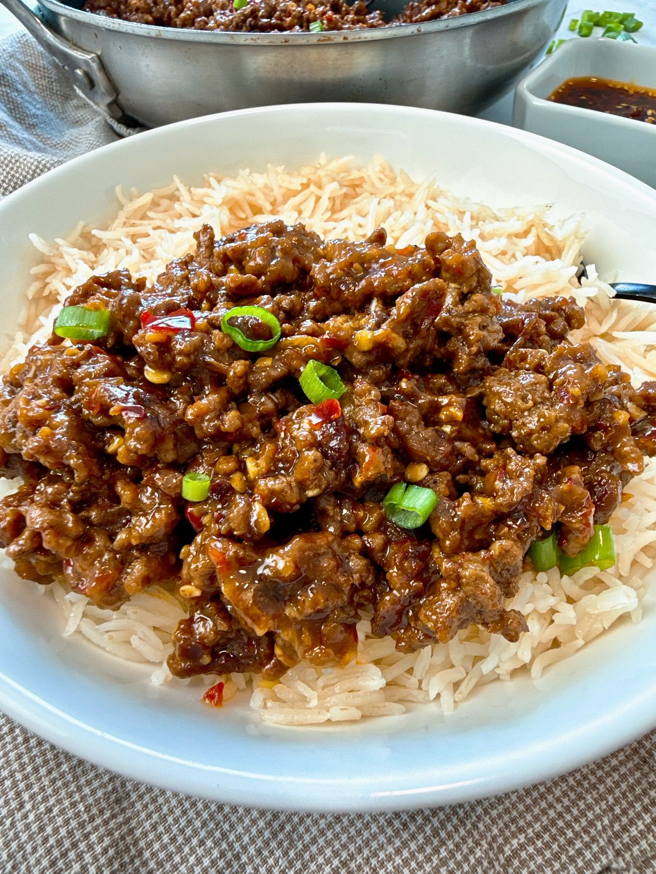 Ground beef and chili crisp over rice in a white bowl